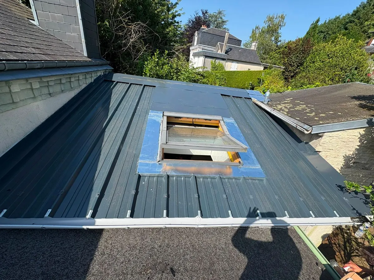La même toiture couverte en bac acier anthracite, avec abergement en zinc et fenêtre de toit neuve