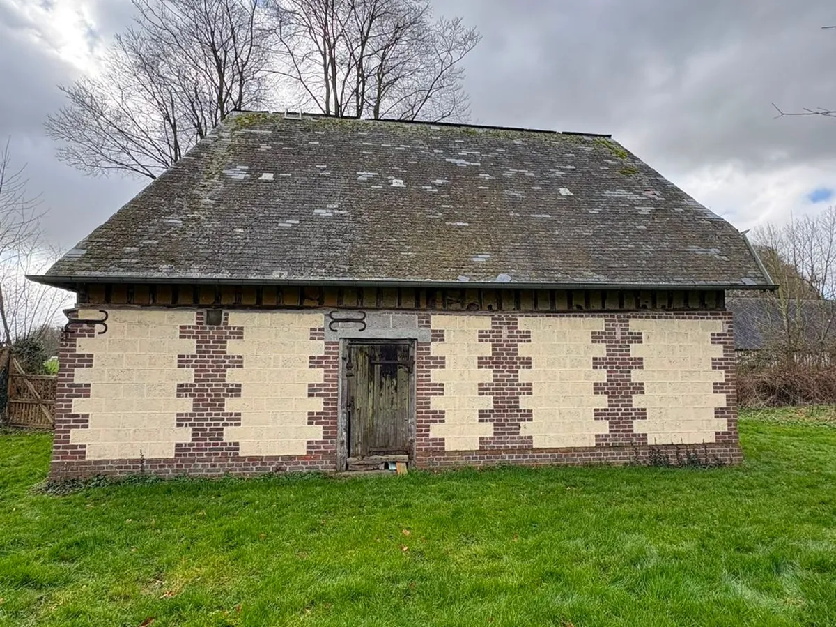 Grange normande à chaînages de brique, toiture d’origine couverte de mousse et d’ardoises dépareillées