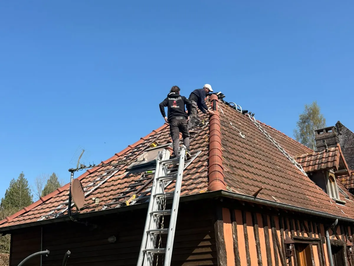 Toiture en cours de dépose sur une maison à colombages, couvreurs au travail