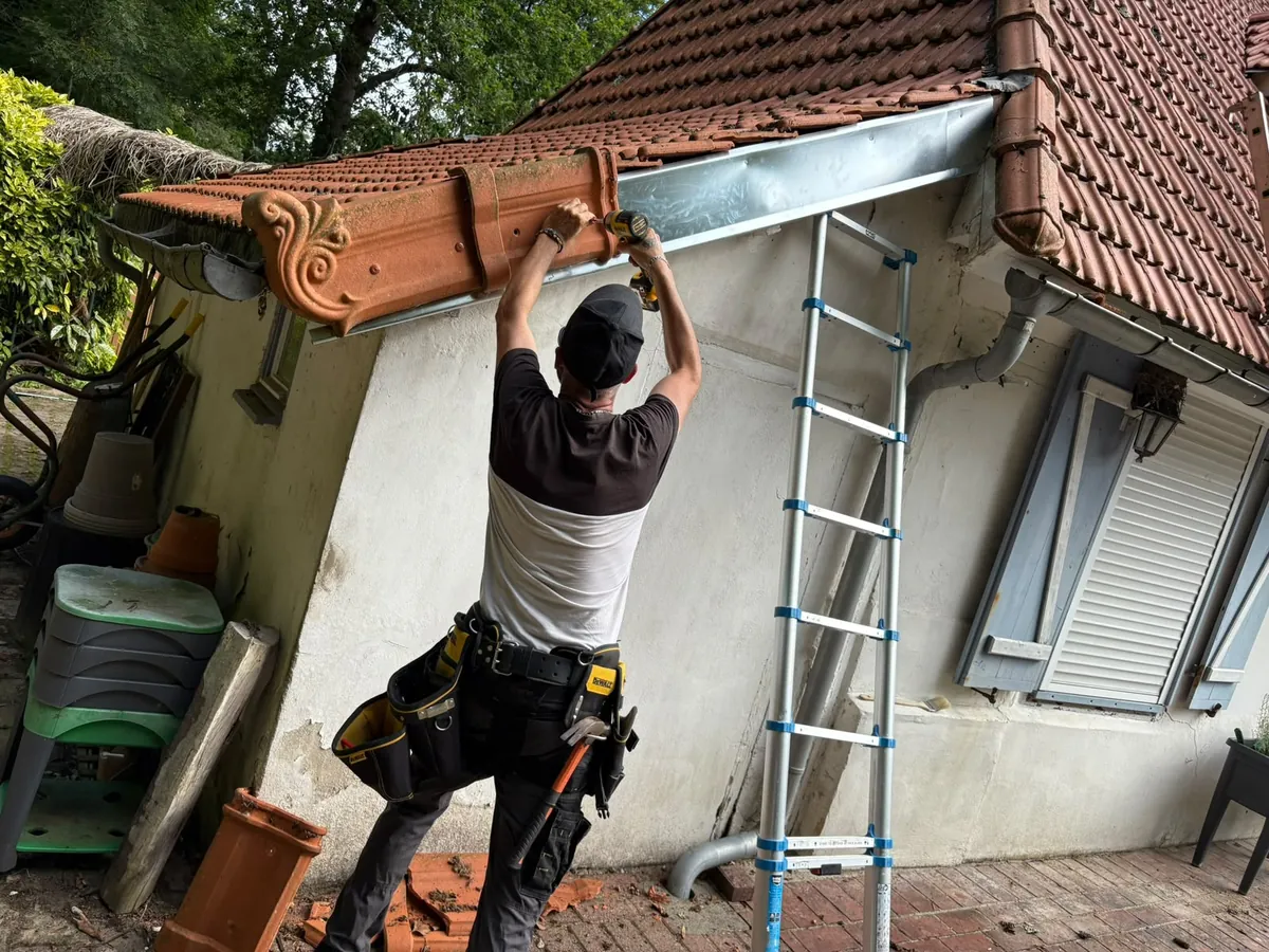 Pose d’une gouttière en zinc neuve sous une toiture en tuile